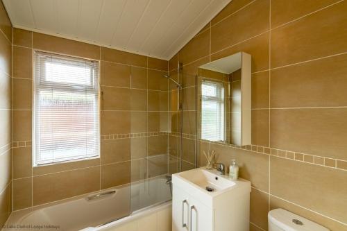y baño con lavabo, aseo y espejo. en Langdale Lodge, en Windermere