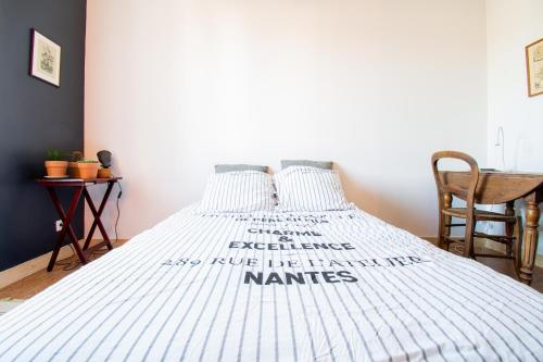 a bed with a white comforter with words on it at Studio cosy sur l’île de Nantes / Proche Tramway in Nantes
