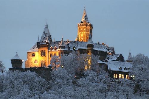 an old castle is lit up in the snow at Fewo-Liza in Wernigerode