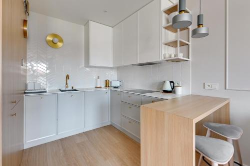 uma cozinha branca com armários brancos e uma mesa de madeira em Grano Residence Comfort Apartments em Gdansk