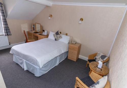 a bedroom with a white bed and a desk at The Quorn Lodge Hotel in Melton Mowbray