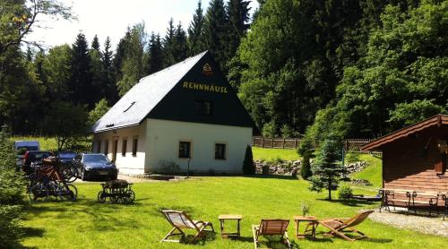 een gebouw met een zwart-wit dak en stoelen in een tuin bij Ferienhaus Bikehütte Rehnhäusl in Fürstenwalde