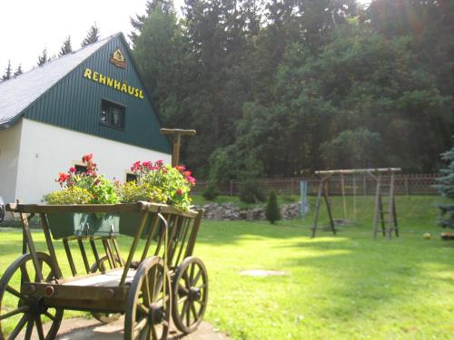 een tuin met een kar met bloemen en een speeltuin bij Ferienhaus Bikehütte Rehnhäusl in Fürstenwalde
