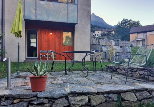 a patio with a table and chairs in front of a house at Maison 4 jardin - Casa design ai margini del bosco in Crodo