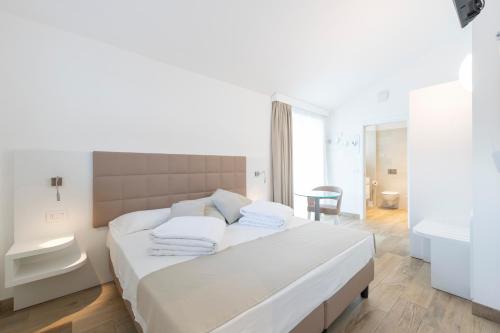a white bedroom with a large bed with white pillows at Gabbiano in Malcesine