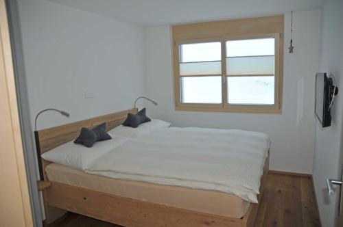 a bedroom with a white bed with a window at Alpen-Park 1. Stock West in Riederalp