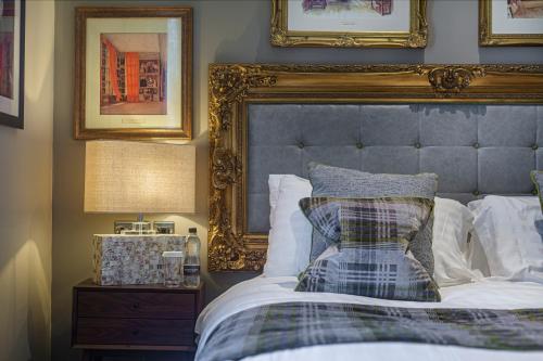 a bedroom with a large bed with a blue headboard at The Rutland Arms Hotel, Bakewell, Derbyshire - The Coaching Inn Group in Bakewell
