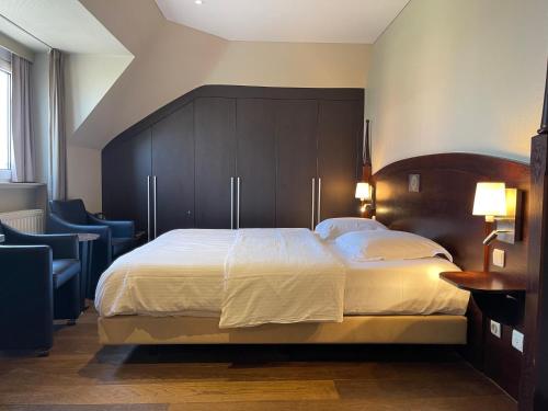 a bedroom with a large bed with a wooden headboard at Villa Hotel (Adults only) in Westende