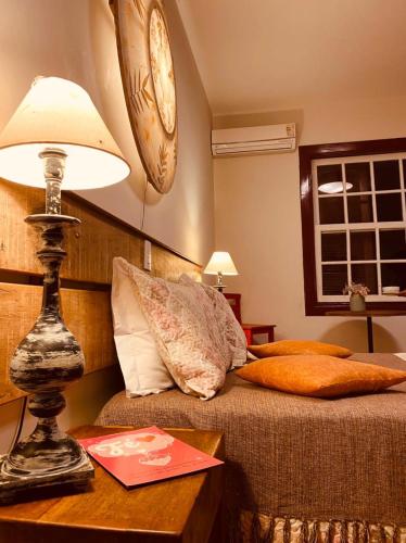 a bedroom with a bed and a table with a lamp at POUSADA CHARLOTTE in Tiradentes