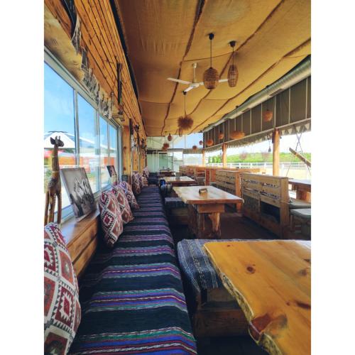 a restaurant with wooden tables and benches and windows at Hotel Frigopan in Plovdiv