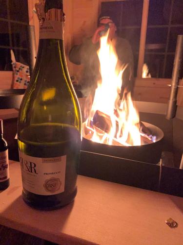 a bottle of wine sitting on a table in front of a fire at Daviot Luxury Pods in Inverness