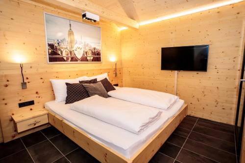 a bed in a wooden room with a flat screen tv at Bergresort Hauser Kaibling by ALPS RESORTS in Haus im Ennstal