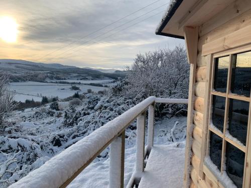 a snow covered balcony of a cabin with a view at Daviot Luxury Pods in Inverness