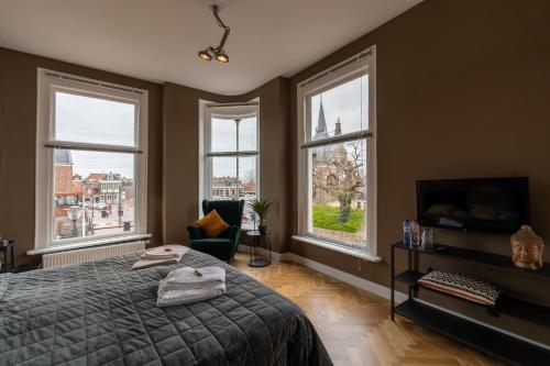 um quarto com janelas, uma cama e uma cadeira em Stadslogement Hoogend em Sneek