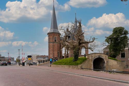 uma igreja com um campanário e uma árvore na rua em Stadslogement Hoogend em Sneek
