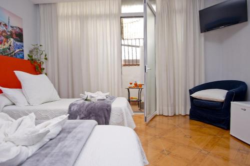 een woonkamer met 2 bedden en een stoel bij Barcelona City Centre Hostal in Barcelona