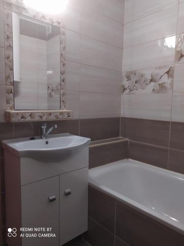 a bathroom with a sink and a bath tub at Apartmanház Gabriella in Harkány