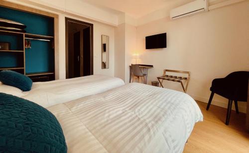 a hotel room with two beds and a table at Hotel Courbet in Juan-les-Pins