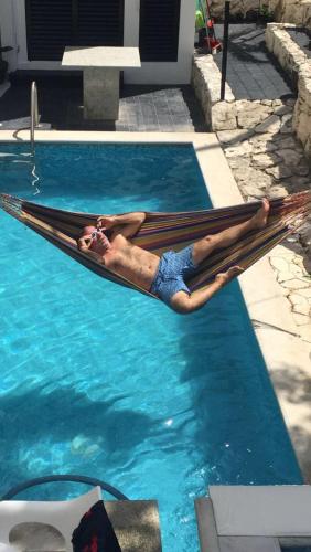 a man laying on a hammock in a swimming pool at Los Balcones Puerto Morelos in Puerto Morelos