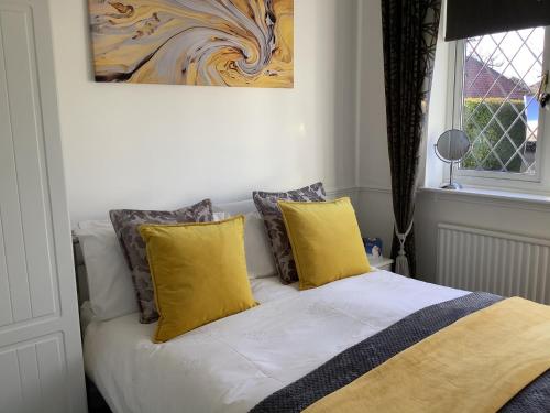 una cama con almohadas amarillas y una pintura en la pared en Ragged Hall Lane, en Saint Albans