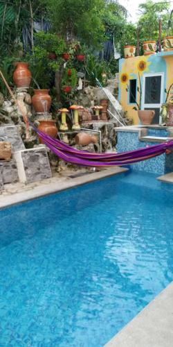 a swimming pool with two hammocks and potted plants at Los Balcones Puerto Morelos in Puerto Morelos