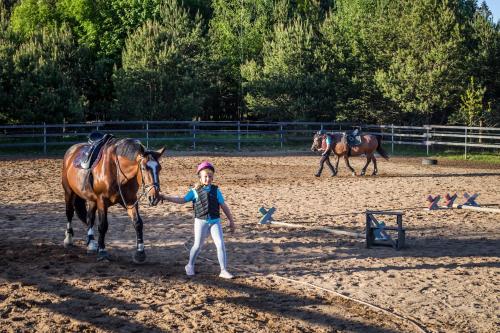 a young girl is standing next to a horse at Gilė -'Virš Ąžuolų' - Forest SPA - Horses - Lake - Chalet in Paplatelė