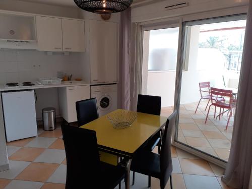 une cuisine et une salle à manger avec une table et des chaises dans l'établissement Arena Résidence, au Cap d'Agde