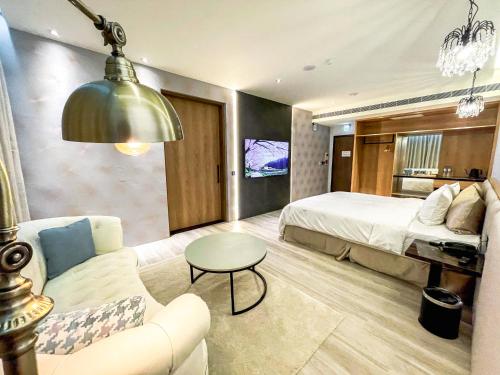 Una habitación de hotel con una cama, un sofá y una mesa. en Fifth Avenue Motel, en Taichung