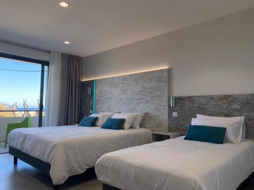 a hotel room with two beds and a large window at Hôtel L'Isula Marina in LʼÎle-Rousse