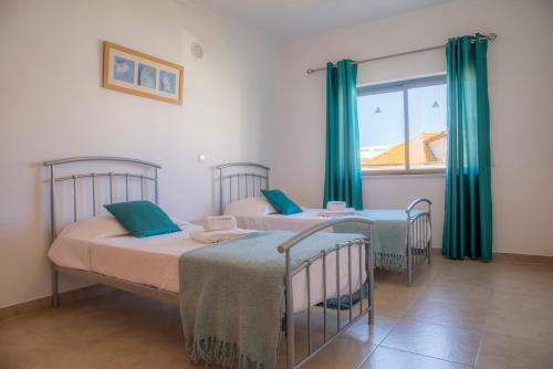 two beds in a room with green curtains and a window at Lagos Central Wellness in Lagos