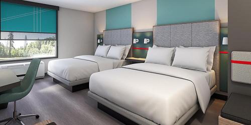 um quarto de hotel com duas camas, uma secretária e uma cadeira em avid hotels - Lexington - Hamburg Area, an IHG Hotel em Lexington