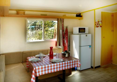 a small kitchen with a table and a refrigerator at Camping Humawaka in Comps-sur-Artuby