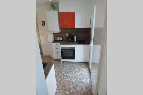 une petite cuisine avec des armoires blanches et une cuisinière dans l'établissement Lady Constantine/plan d'eau, à Vichy