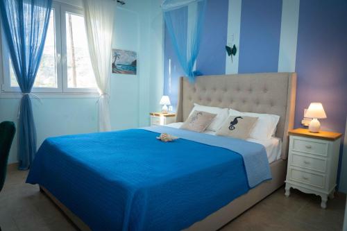 um quarto azul com uma cama grande e um cobertor azul em Seaside Apartments em Kaloí Liménes