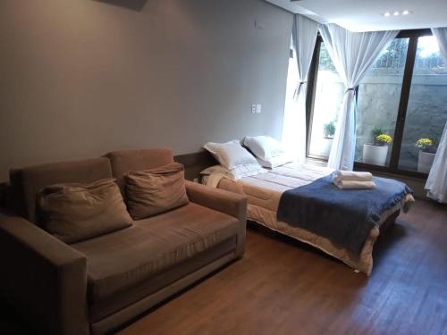 uma sala de estar com um sofá, uma cama e uma janela em Studio próximo ao centro de gramado em Gramado