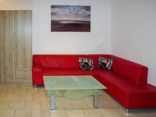 a red couch in a living room with a table at Apartment Gartenstraße-1 by Interhome in Ostseebad Karlshagen