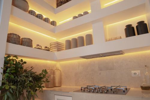 a kitchen with white walls and a stove with shelves at Palazzo Lecce - Epoca Collection in Lecce