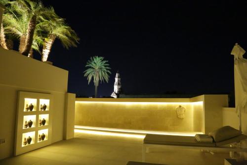 a patio at night with palm trees and a clock tower at Palazzo Lecce - Epoca Collection in Lecce
