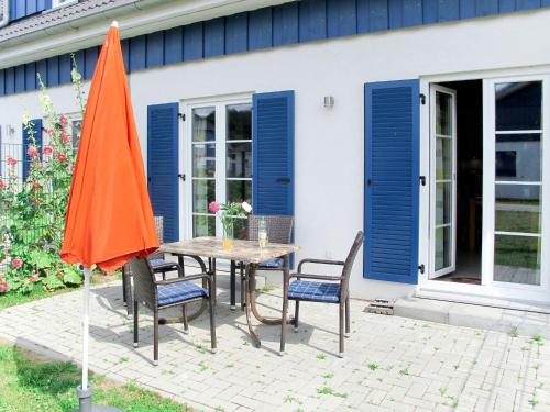 a table and chairs with an orange umbrella on a patio at Holiday Home Rügenperle by Interhome in Altefähr