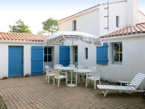 un patio avec une table, des chaises et un parasol dans l'établissement Holiday Home Les Brisans by Interhome, à La Tranche-sur-Mer