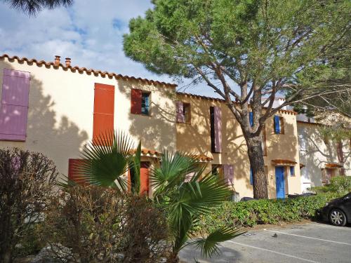 a building with red and blue windows and a tree at Holiday Home Marina 1 by Interhome in Saint-Cyprien-Plage