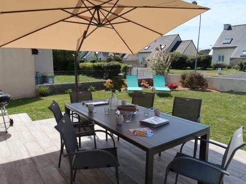 une table et des chaises avec un parasol sur une terrasse dans l'établissement Holiday Home Les Camélias by Interhome, à Perros-Guirec
