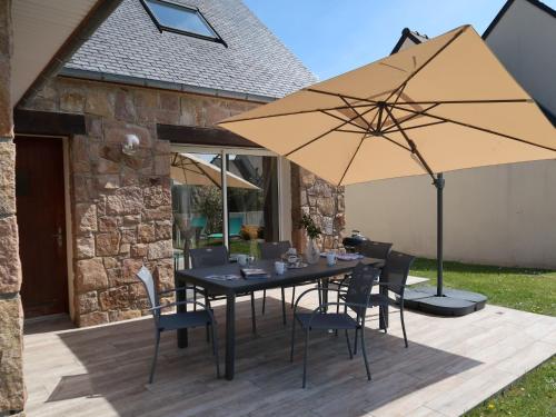 une table avec des chaises et un parasol sur une terrasse dans l'établissement Holiday Home Les Camélias by Interhome, à Perros-Guirec