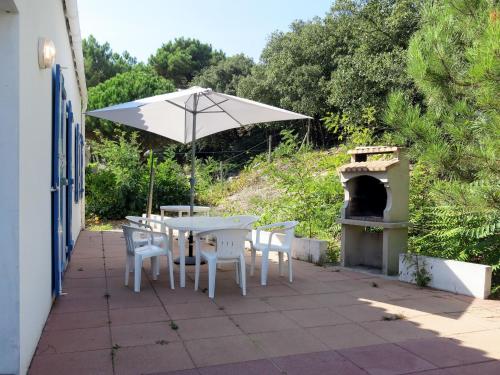 une table et des chaises avec un parasol sur une terrasse dans l'établissement Holiday Home Les Tourteaux by Interhome, à La Tranche-sur-Mer