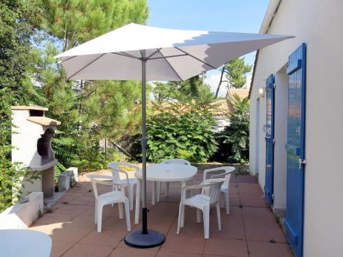 - une table blanche avec des chaises et un parasol sur la terrasse dans l'établissement Holiday Home Les Tourteaux by Interhome, à La Tranche-sur-Mer