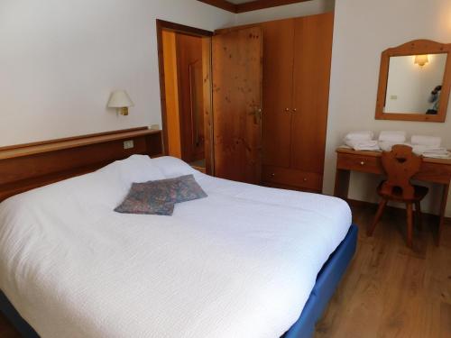 a bedroom with a white bed and a mirror at Ski Residence in San Martino di Castrozza