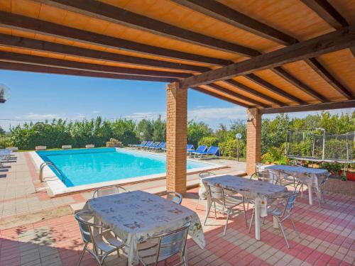 patio ze stołami i krzesłami oraz basenem w obiekcie Holiday Home Coast-2 by Interhome w mieście Bibbona