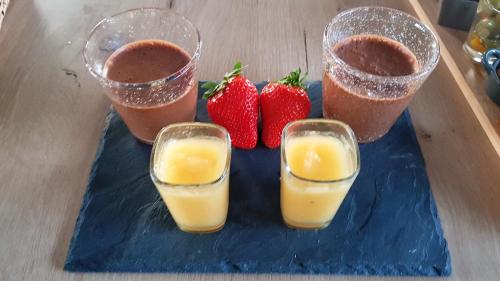 three glasses of orange juice and strawberries on a blue plate at Charmante Maison avec jardin à Mornas in Mornas