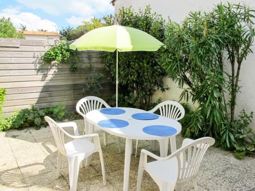 a table with a green umbrella and four chairs at Holiday Home La Touche - IDR121 by Interhome in La Flotte