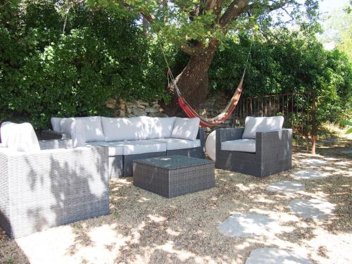 3 Korbstühle und eine Couch im Hof in der Unterkunft Holiday Home Le Chêne - SRX100 by Interhome in Sabran